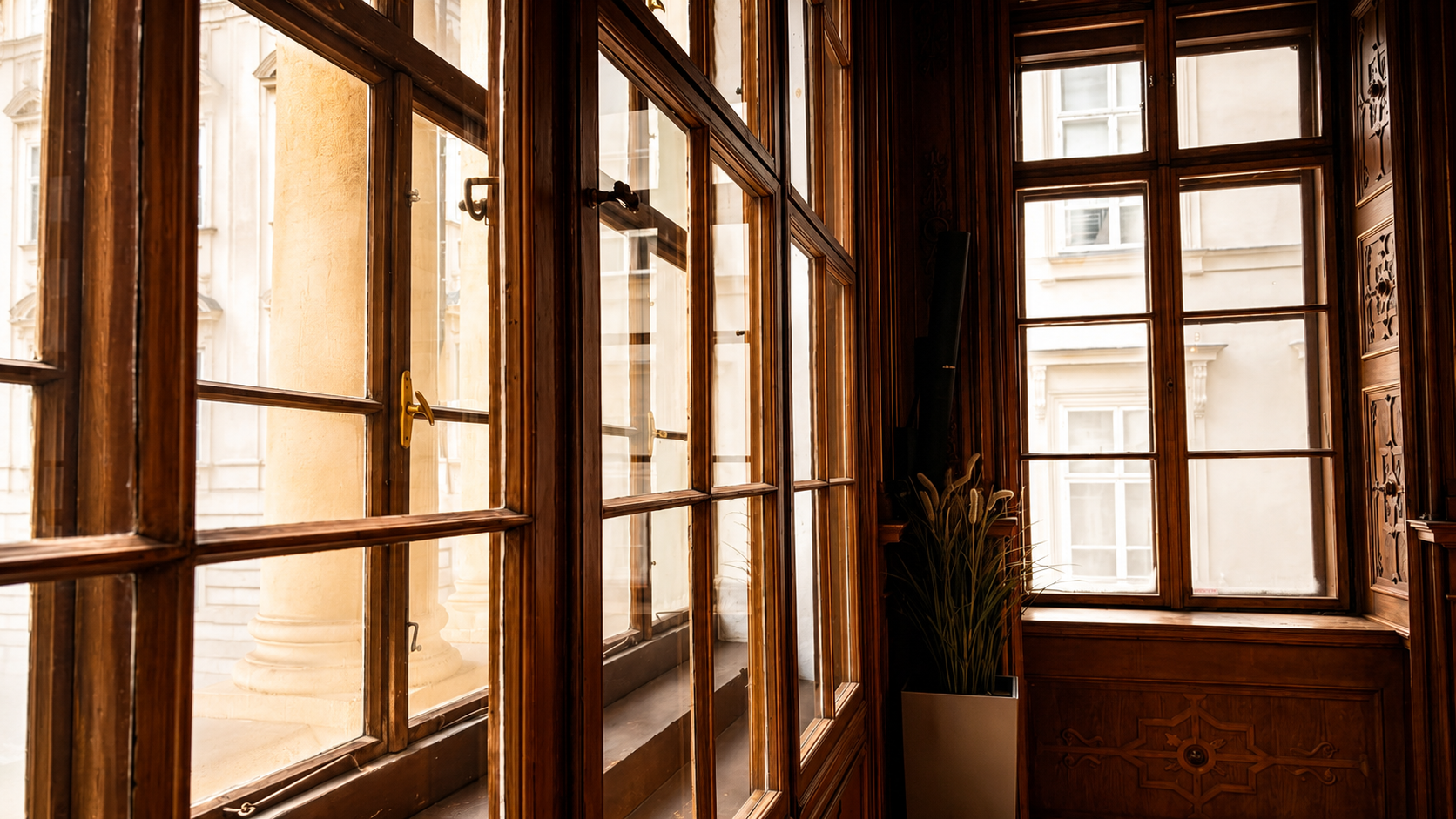  Blick durch historische Holzfenster im Palais Niederösterreich – warmes Licht fällt in den Innenraum, im Hintergrund die Wiener Altstadt.